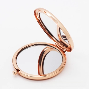 Detail view of foldable rose gold metal makeup mirror with dual-sided magnification