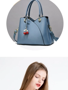Macro detail of blue leather handbag featuring gold leaf and red cherry charm pendant