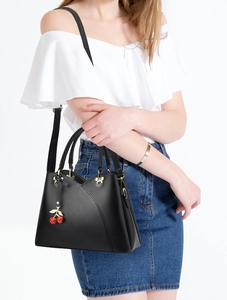Detail of black leather handbag with Mickey-shaped gold hardware and cherry charms