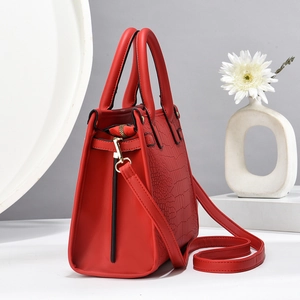 Detail of red crossbody bag with smooth and crocodile embossed leather textures