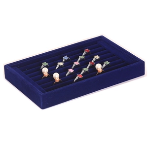 Close-up of deep blue velvet jewelry tray with multiple slots for rings and earrings