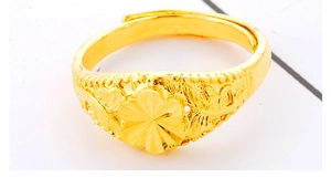 Close-up of golden ring featuring intricate floral and leaf relief with adjustable open band