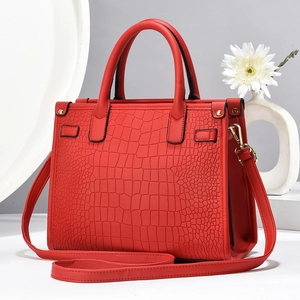 Macro shot of red faux crocodile leather texture and gold hardware on elegant handbag