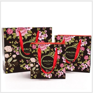 Three sizes of floral black gift bags with red ribbon handles and beautiful text detail