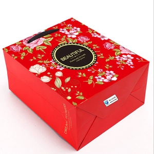 Close-up of red floral gift bag side view showing handle and printed text details