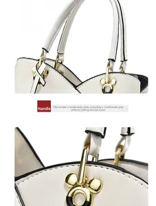 Detail of white leather handbag with black edges and gold Mickey-shaped metal buckle