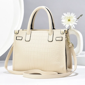 Detail of a beige crocodile pattern handbag with elegant gold hardware and top handles