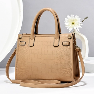 Detail of camel brown faux crocodile leather texture on elegant women's handbag