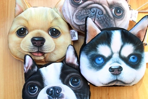 Overhead view of four plush dog head coin purses featuring pug and husky designs