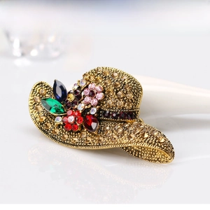 Detail of vintage gold sun hat brooch with amber crystals and colorful floral rhinestones
