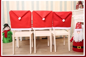 Detail view of three red Santa hat chair covers set on white chairs in a festive room