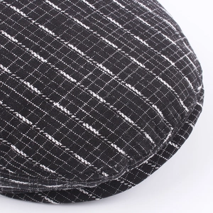 Close-up of black and white checkered flat cap in premium woven fabric texture