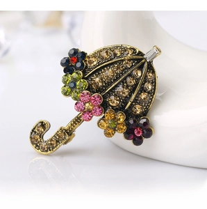 Detail of vintage umbrella brooch with colorful crystals on a white swan display
