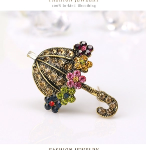 Detailed close-up of vintage umbrella brooch with colorful rhinestones and gold alloy