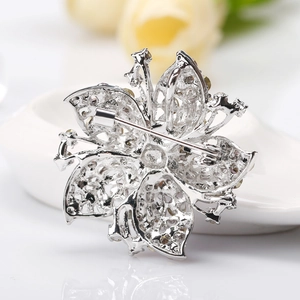 Classic silver floral crystal brooch with sparkling diamonds on a white surface