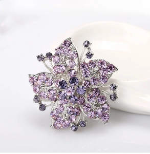 Macro shot of silver alloy flower brooch with sparkling purple crystals and rhinestones