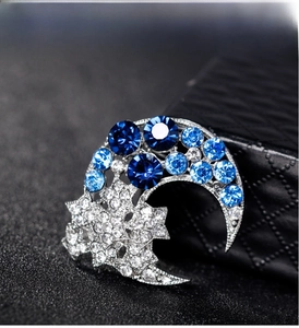 Macro detail of silver star and moon brooch with blue and clear inlaid crystals