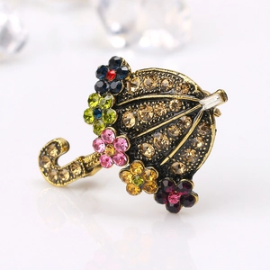 Vintage umbrella brooch in bronze alloy with colorful rhinestones on a white surface