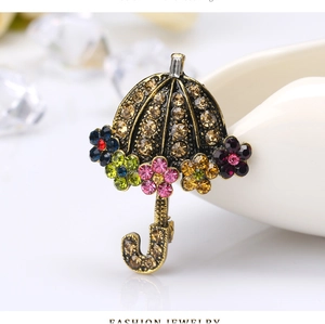 Close-up of vintage golden umbrella brooch with colorful crystal flowers and champagne rhinestones