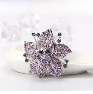 Macro shot of purple flower crystal brooch with sparkling rhinestones on white plate