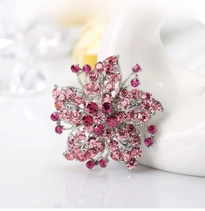 Macro shot of a floral crystal brooch featuring pink gradient rhinestones and silver metal