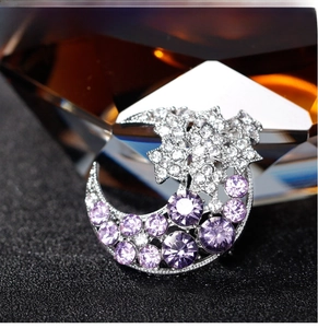 Macro detail of star and moon brooch with purple rhinestones and silver metal base