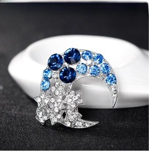 Detailed view of silver moon and star brooch with sparkling blue and clear rhinestones
