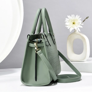 Detail view of sage green tote bag with crocodile texture and gold hardware zipper