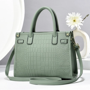 Close-up of mint green crocodile-embossed PU leather texture and gold hardware detail
