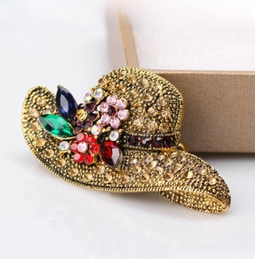 Detailed close-up of retro golden hat brooch with champagne crystals and colorful gems