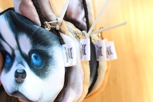 Close-up of stacked plush husky coin purses with blue eyes, tassels, and brand tags
