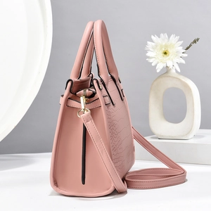 Pink crocodile-embossed handbag featuring elegant gold hardware and a long crossbody strap