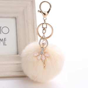 Close-up of a rhinestone ballerina charm with a soft cream plush pom pom keychain