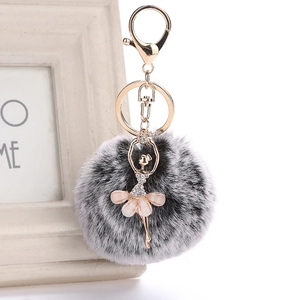 Detail of a ballet dancer pendant with a fluffy faux fur pompom on a gold keychain