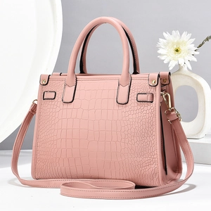Detail view of pink crocodile embossed leather handbag with golden metal hardware and strap