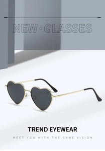 Detailed view of heart-shaped sunglasses with golden metal frame and dark grey lenses