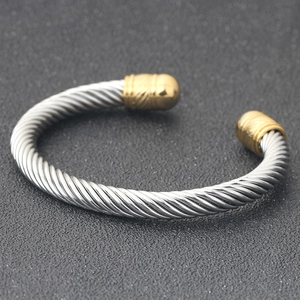 Detail of a 7mm silver twisted cable cuff bracelet with elegant gold decorative end caps