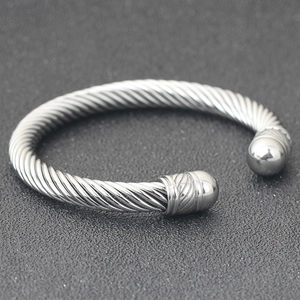 Close-up of a silver twisted cable open bangle with decorative round beads at the ends