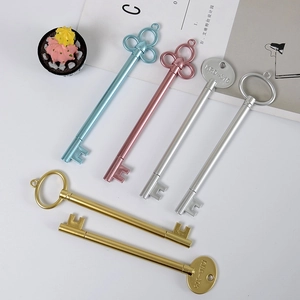 Retro key-shaped gel ink pens in metallic gold, silver, and blue on a minimal desk set