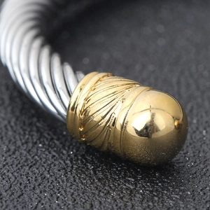 Macro shot of 7mm silver cable wire bracelet with detailed golden textured end cap