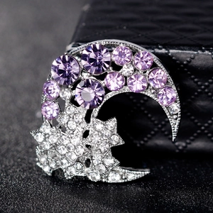Fashion star and moon alloy brooch with purple rhinestones on a black textured background