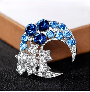 Macro shot of silver crescent moon and star brooch set with blue and clear rhinestones