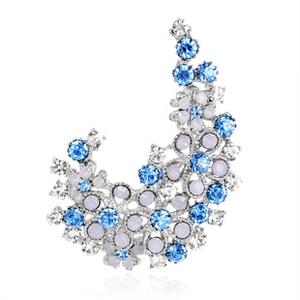 Macro detail of crescent brooch with blue and clear crystals on silver metal base