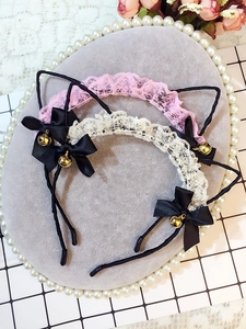 Detail of pink and white lace cat ears headband with black bows and golden bells