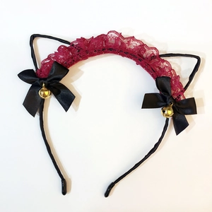 Close-up of cute cat ear headband with red lace trim, black bows and golden bells