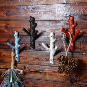 Rustic branch-shaped cast iron wall hooks in black, white, blue and red on wood background