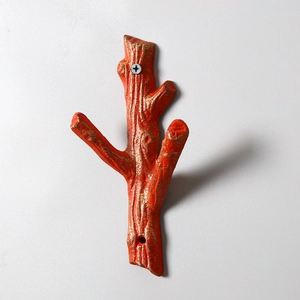 Detail of vintage cast iron branch hook with orange finish and realistic bark texture