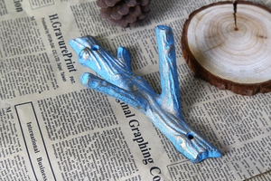 Detail of vintage blue and gold iron branch wall hook with rustic tree bark texture