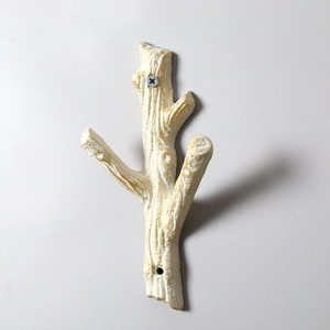 Macro shot of branch-shaped white iron hook with gold details and wall mounting holes
