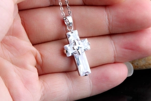 Close-up of hand-held silver cross pendant with square-cut AAA cubic zirconia stones